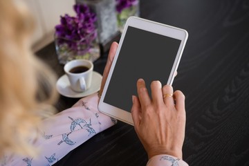 Businesswoman using digital tablet by coffee cup in cafe