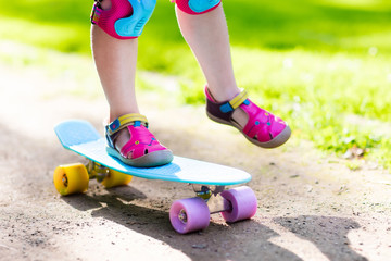Child riding skateboard in summer park