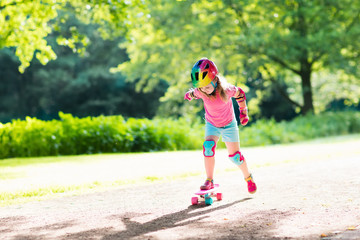 Child riding skateboard in summer park