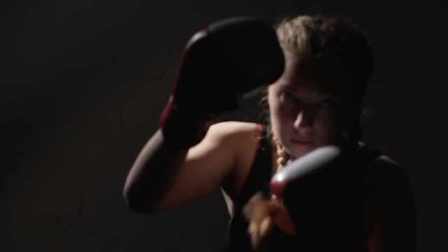 Aggressive female Muay Thai boxer training before fight, self-defense course