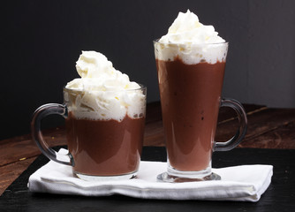 Hot chocolate cocoa with whipped cream on vintage wooden background, selective focus