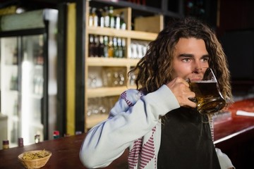 Man having beer while leaning against counter