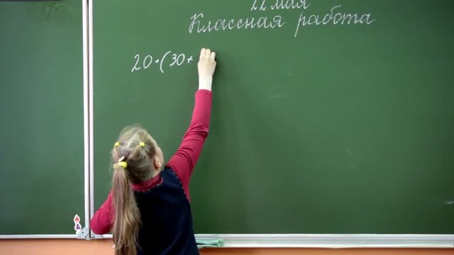 Russian young student decides mathematics on the school blackboard in the classroom. School is in Russia