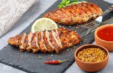 Chicken breast grilled with spices and sauce on the table. Dinner in a rustic style. Selective focus