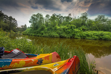 Kayaks sitting on a green grassy riverbank.