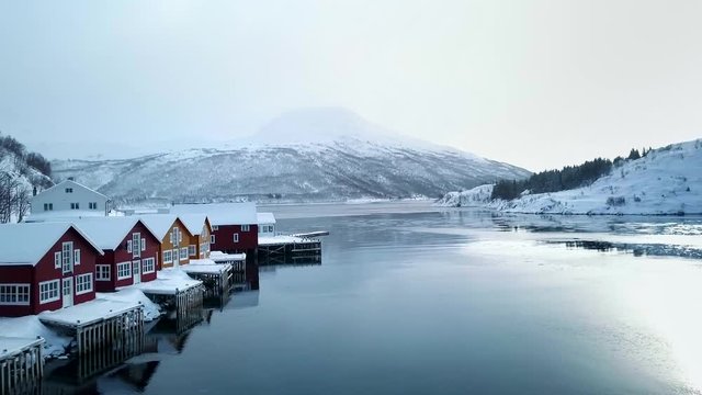 Drone flight over ice lake with norwegian huts