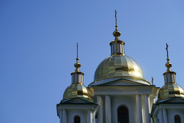 Fototapeta na wymiar Glittering domes of a Christian Church on the background of blue cloudless sky