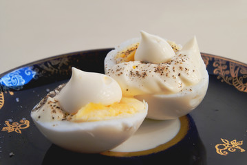 Two halves of boiled egg with sauce and pepper