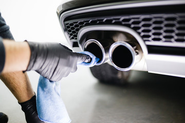 A man cleaning car exhaust with microfiber cloth, car detailing (or valeting) concept. Selective focus. 