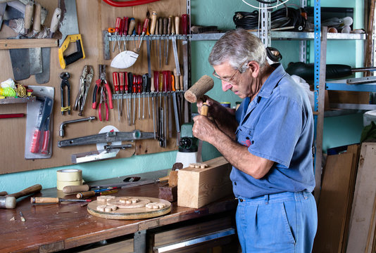 cabinetmaker carving wood with a chisel and hammer in workbench