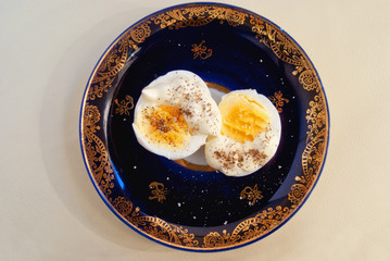 Two halves of boiled egg with sauce and pepper