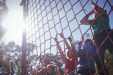 Group of fit woman climbing a net during course 