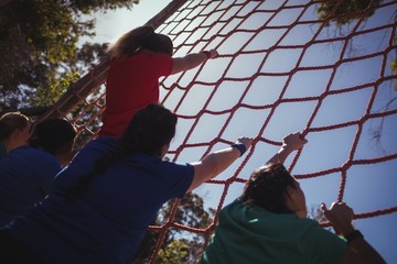 Group of fit woman climbing a net during course