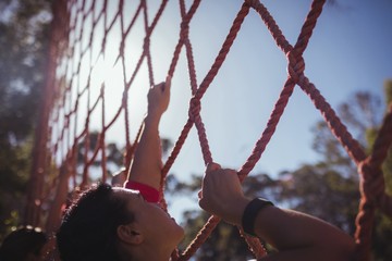 Fit woman climbing a net during obstacle course training