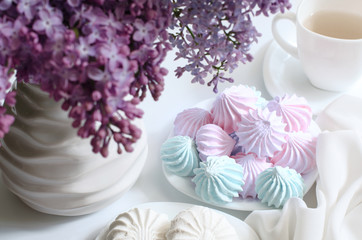 Marshmallows on a table with lilac flowers. Sweets in the kitchen.