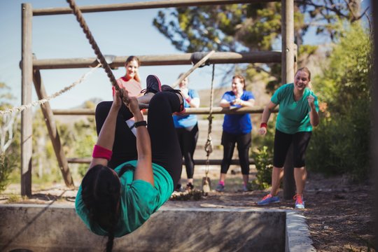 Fit woman climbing a rope during obstacle course training