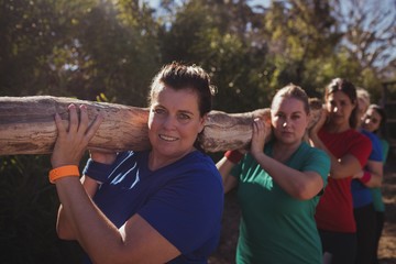 Group of fit women carrying a heavy wooden log 