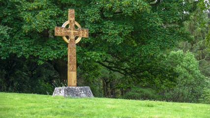 Carved wooden cross in garden setting.