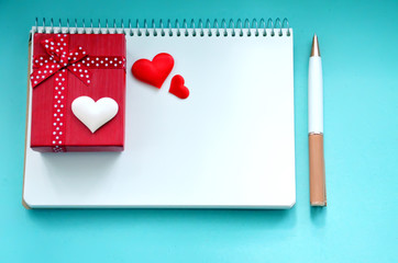 Red and white hearts, gift box and pen on a blue background