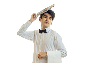 handsome young waiter got tired and put on the head of an empty dish podnom close-up