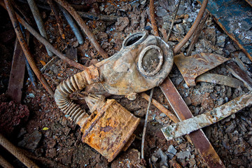 Old rotten Soviet gas mask with rusty filter on rusty metal floor of ship with garbage 