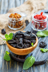 Dried black plums in a wooden bowl.