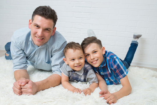 Happy family, father and two sons having fun lying on the floor