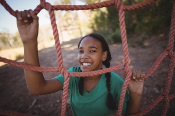 Portrait of happy girl standing near net during obstacle course