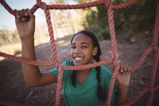 Portrait of happy girl standing near net during obstacle course