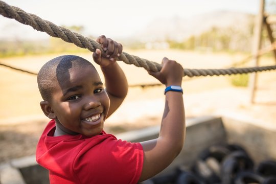 Portrait of happy boy crossing the rope during obstacle course