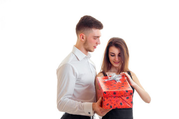 a young girl is standing next to a charming guy, and opens a gift