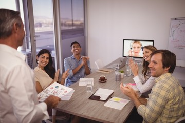Colleagues applauding for man giving presentation