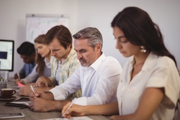 Business people noting on paper during meeting