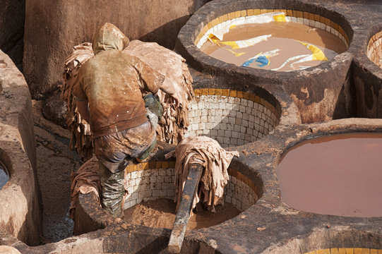 FEZ, MOROCCO - FEBRUARY 20, 2017: Unidentified men working within the paint holes at the famous Chouara Tannery in the medina of Fez, Morocco. The leather tannery dates back to the 11th century AD. 