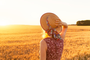 Back view of girl in yellow field at sunset