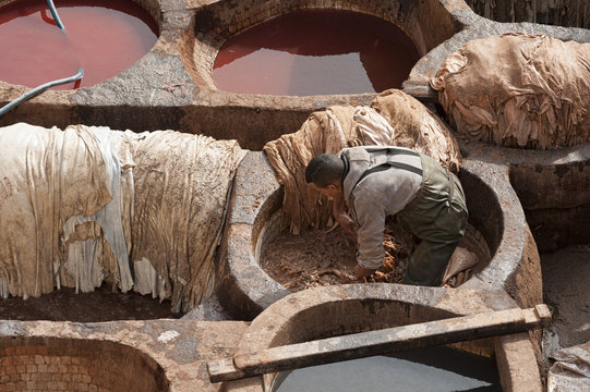 FEZ, MOROCCO - FEBRUARY 20, 2017: Unidentified men working within the paint holes at the famous Chouara Tannery in the medina of Fez, Morocco. The leather tannery dates back to the 11th century AD. 