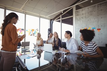 Naklejka premium Businesswoman giving presentation to colleagues in office