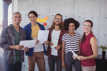 Cheerful business people standing in creative office