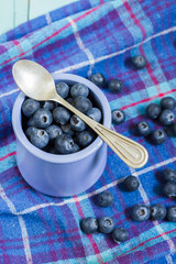 Blueberries in cup. Blue wooden table, blue kitchen towel.
