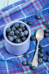 Blueberries in cup. Blue wooden table, blue kitchen towel.