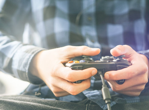Male hands holding a joystick controller while playing a video games at home - Gaming, entertainment, technology and people concept