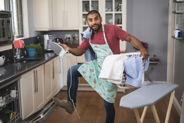 Portrait of man holding laundry basket and iron 