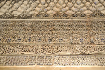 GRANADA, SPAIN - FEBRUARY 10, 2015: A close-up view to calligraphy decorated details of a wall at palace of Alhambra, Granada, Andalusia, Spain.