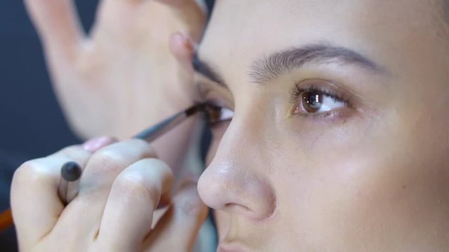 Makeup artist apply makeup to an attractive young women. Beauty Woman Make-up.