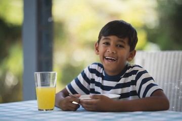 Portrait of happy boy having breakfast at table