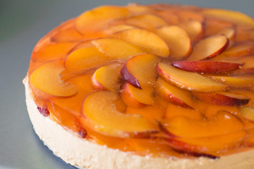 Fruit cake with peach, jelly and mousse in plate on gray background.