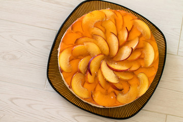 Fruit cake with peach, jelly and mousse in plate on wooden background. Aerial view.