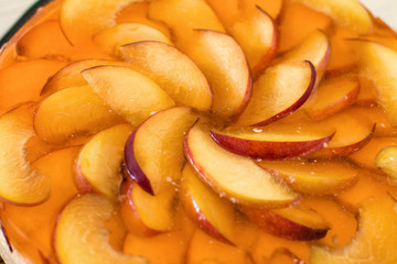 Fruit cake with peach, jelly and mousse in plate on wooden background.
