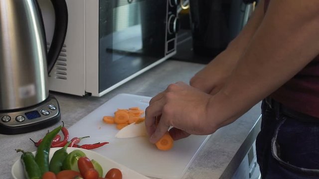 Man carefully carving carrots to make delicious dinner for his girlfriend