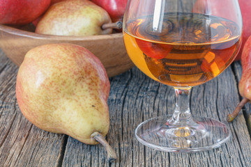 Bottle of pear aguardiente brandy and fresh pear on rustic dark background